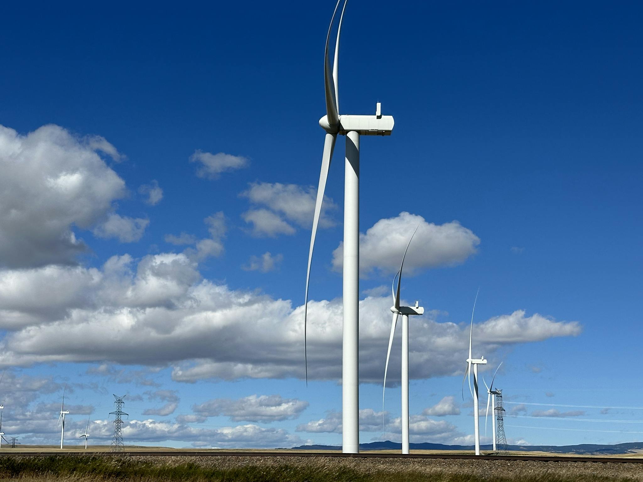 Wind turbines in open landscape with blue sky gathering wind energy
